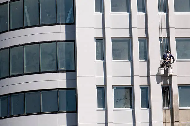 Commercial building facade with a professional painter applying an exterior finish by an exterior painter in San Mateo, CA.
