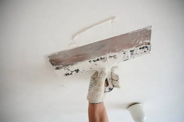 Smoothing a ceiling surface during popcorn ceiling removal by a painting company in San Carlos, CA.
